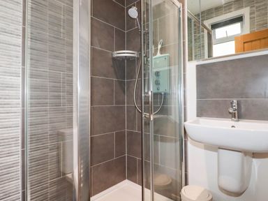 A bathroom with a shower, sink, and toilet at Apartment 1 in Newquay
