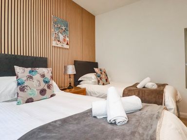 Two beds with pillows and linens set in a bedroom at Apartment 1 in Newquay