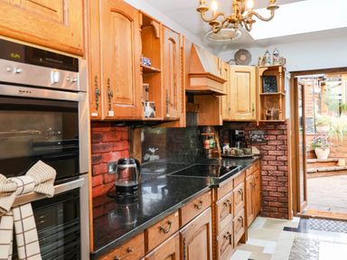 A kitchen with wooden cabinets and modern appliances at Severnwolf House in Gloucester