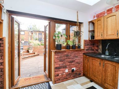 A kitchen with wooden cabinets and a view of a garden at Severnwolf House, Gloucester