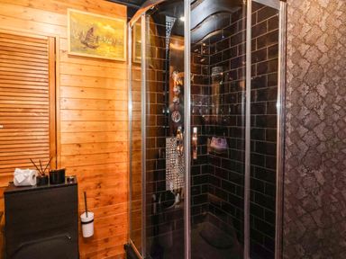 A shower with black tiles in a bathroom at Severnwolf House in Gloucester