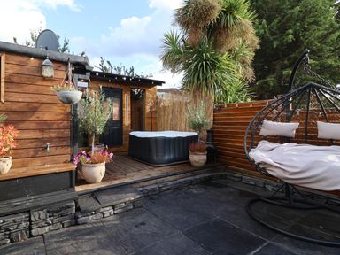 An outdoor area with a hot tub and hanging chair at Severnwolf House in Gloucester