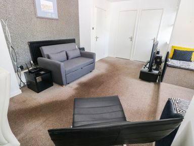 A living room with a sofa, television, and radiator at 21 Ferrara Square in Swansea