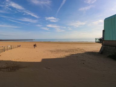 A beach with people walking and a building at 21 Ferrara Square Swansea