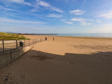 A beach with sand and people walking at 21 Ferrara Square Swansea