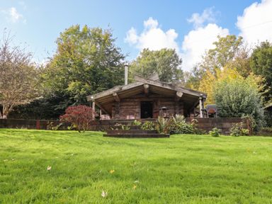 A log cabin with outdoor seating and garden at Thimble Lodge in Gunnislake