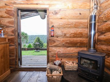 A living room with a door opening to a view at Thimble Lodge in Gunnislake