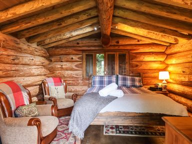 A bedroom with a bed and seating area at Thimble Lodge in Gunnislake