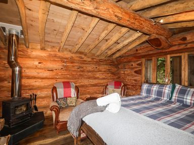 A bedroom with a bed and chairs at Thimble Lodge in Gunnislake