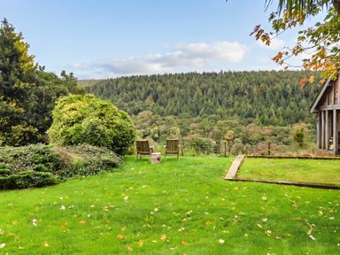 A garden with chairs and greenery at Thimble Lodge in Gunnislake