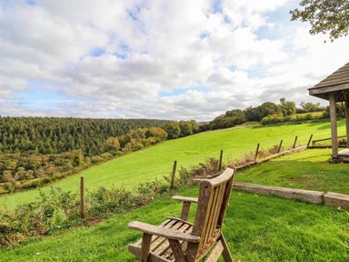 A scenic view with a chair and trees at Thimble Lodge in Gunnislake