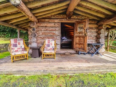 A log cabin with chairs and a table at Thimble Lodge in Gunnislake