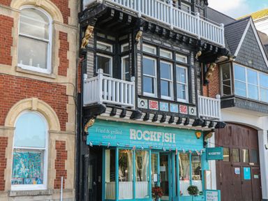 A restaurant with a blue sign and balcony at 1 Embankment House in Dartmouth
