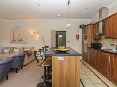 A kitchen with a sofa and bar stools at 1 Embankment House in Dartmouth