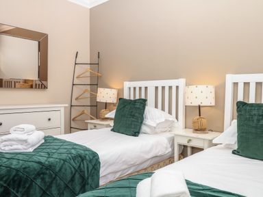 A bedroom with two single beds and a mirror at 1 Embankment House in Dartmouth