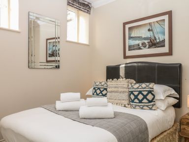 A bedroom with a bed, pillows, and a mirror at 1 Embankment House in Dartmouth