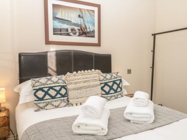 A bedroom with a bed, pillows, and towels at 1 Embankment House, Dartmouth
