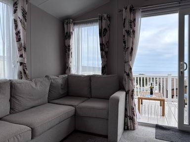 A living room with a sofa and view to a deck at Club Sahara, Sandy Bay, Exmouth