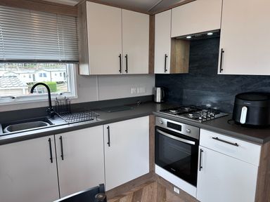 A kitchen with a stove, oven, sink, and air fryer at Club Sahara in Sandy Bay, Exmouth