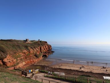 A beach with cliffs and people at Club Sahara Sandy Bay Exmouth