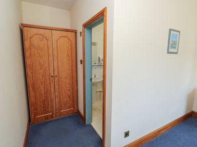 A hallway with a wardrobe and a door leading to a bathroom at Willow in Kingsteignton