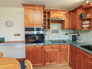 A kitchen with wooden cabinets and appliances at Moorhen in Kingsteignton