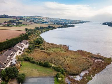 A river surrounded by fields and residential buildings at Moorhen in Kingsteignton