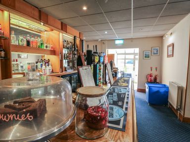 A bar counter with liquor bottles and pastries at Nightjar in Kingsteignton