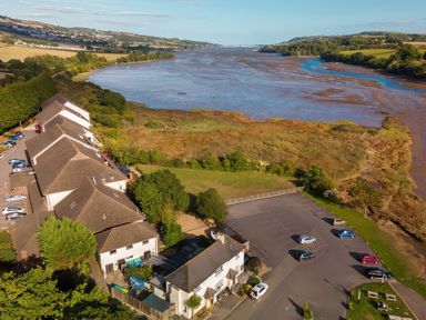 An aerial view of a river with buildings and parking area at Guillemot in Kingsteignton