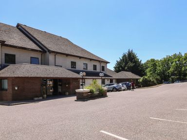 A building with a parking lot and trees at Egret in Kingsteignton