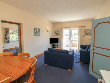 A living room with a sofa and dining table at Egret in Kingsteignton