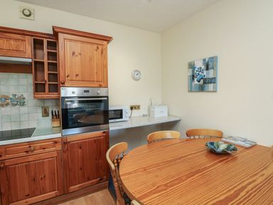 A kitchen with wooden cabinets and a round table at Egret in Kingsteignton