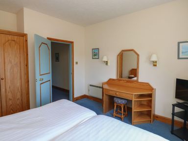 A bedroom with two beds and a vanity table at Egret in Kingsteignton