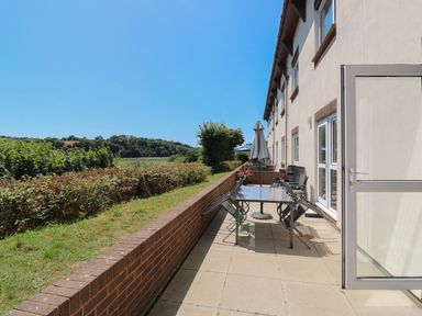 An outdoor patio with a table and chairs at Egret in Kingsteignton