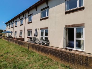 A building with patio chairs and an umbrella at Egret in Kingsteignton