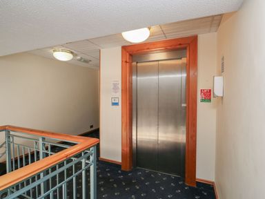 A hallway with an elevator and handrail at Egret in Kingsteignton