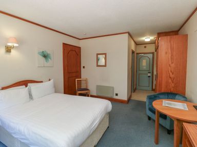 A bedroom with a bed and a chair at Sycamore in Kingsteignton
