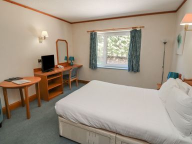 A bedroom with a bed and desk at Sycamore in Kingsteignton