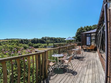 An outdoor deck with tables and chairs at Sycamore in Kingsteignton
