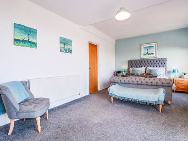 A bedroom featuring a bed with nightstands and wall art at Harber Rise, Carlyon Bay
