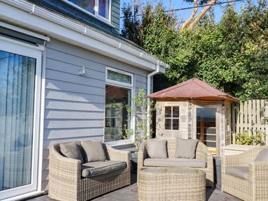 A garden with seating area and wooden shed at Harber Rise in Carlyon Bay