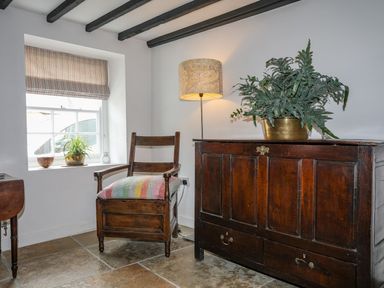 A room with a chair, a lamp, a plant, and a chest at Swn y Mor (Wexham) Beaumaris