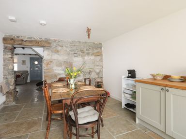 A dining room with a wooden table and chairs at Swn y Mor (Wexham) Beaumaris
