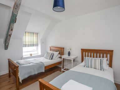 A bedroom with two single beds and a bedside table at Swn y Mor (Wexham) Beaumaris
