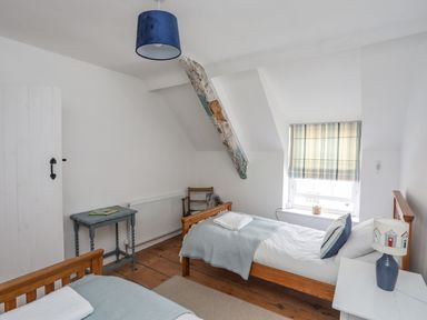 A bedroom with two beds and a table at Swn y Mor (Wexham) Beaumaris