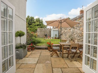 A garden area with outdoor seating and plant pots at Swn y Mor (Wexham) Beaumaris