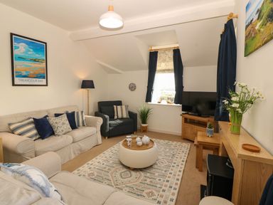 A living room with sofas, a television, and a window at Llywelyn in Trearddur Bay