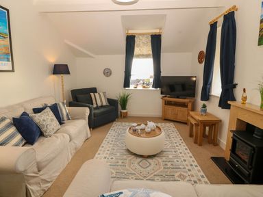 A living room with a sofa and tv at Llywelyn in Trearddur Bay