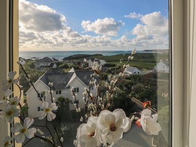 A view from a window showing flowers and houses near the ocean at Llywelyn Trearddur Bay