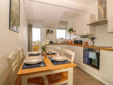 A kitchen with dining table and chairs at Llywelyn in Trearddur Bay